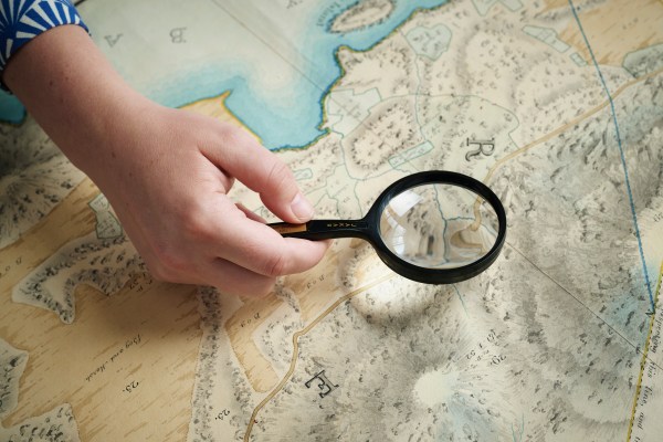 Researcher viewing a map detail with a magnifying glass