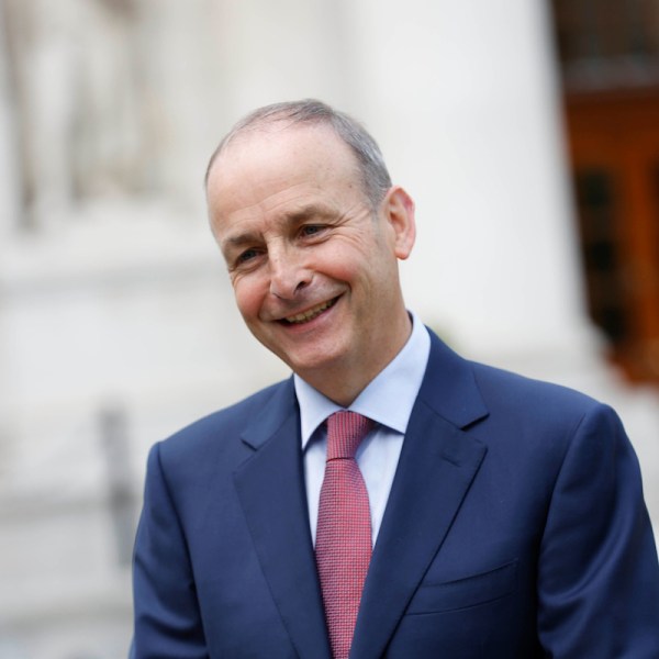 Man in a suit with red tie smiling to the camera