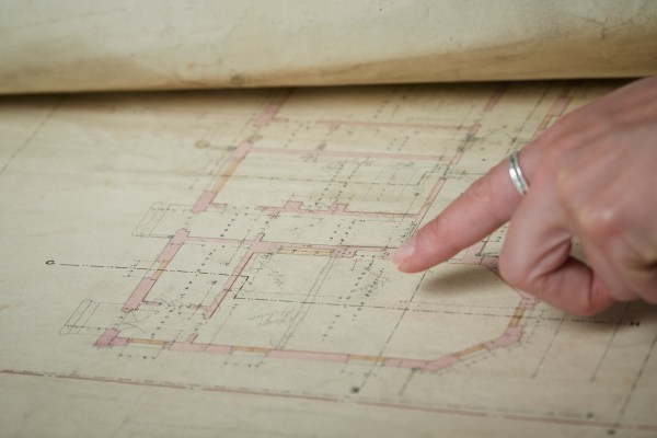 A researcher pointing to a detail on an architectural drawing