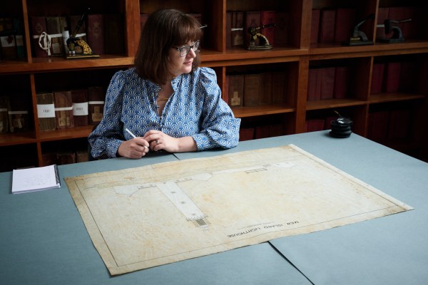 NAI staff member sitting and thinking in front of a plan drawing of a lighthouse.